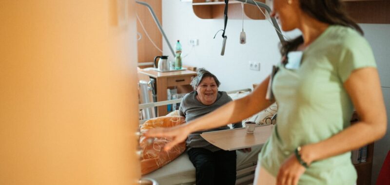 A caregiver interacts warmly with an elderly patient in a retirement home's cozy setting.