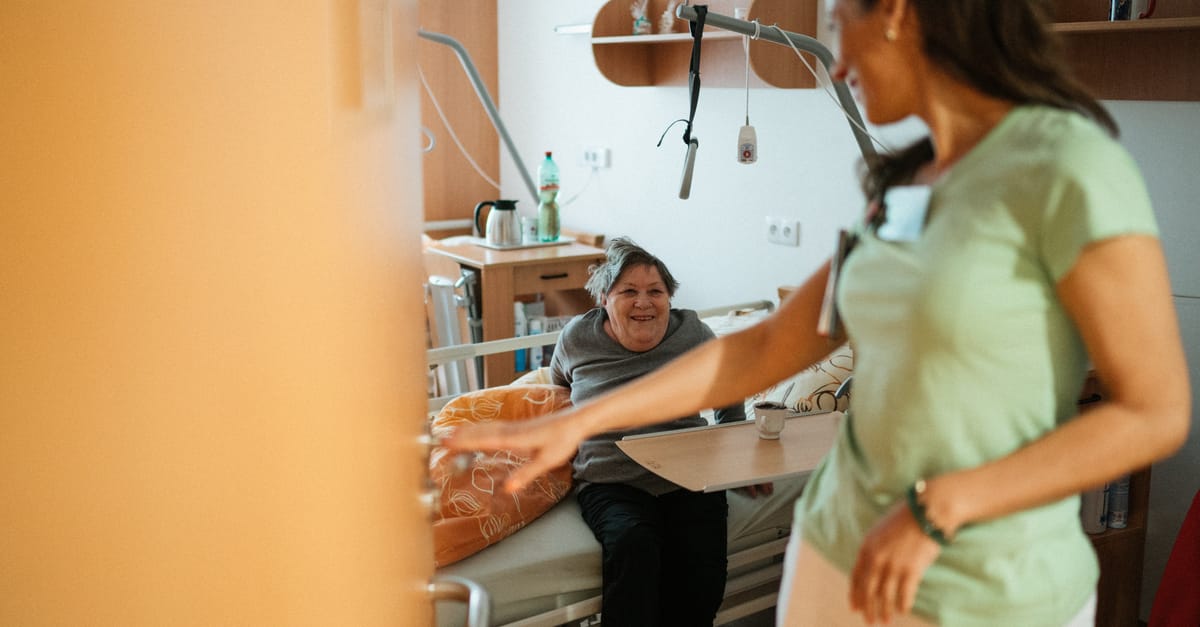 A caregiver interacts warmly with an elderly patient in a retirement home's cozy setting.